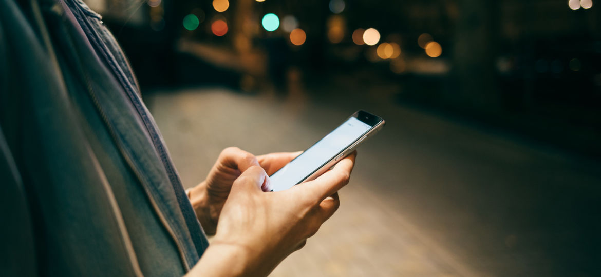 Girl typing message on smart phone on background bokeh lights