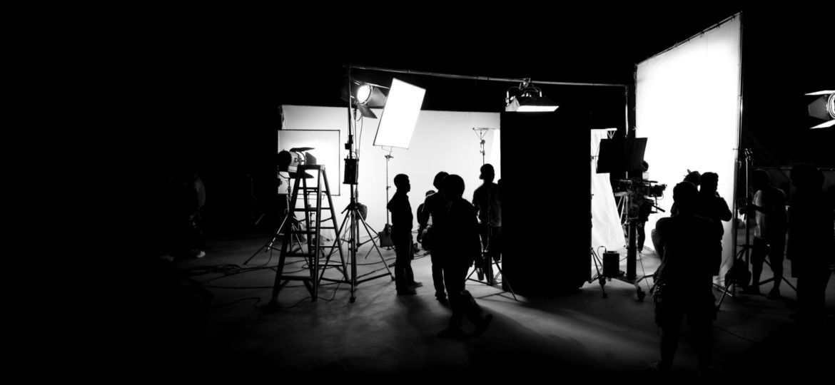 Silhouette images of video production behind the scenes or b-roll or making of TV commercial movie that film crew team lightman and cameraman working together with director in big studio