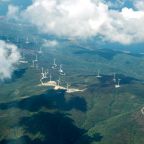 Panorama skyline view of cloudy blue sky from airplane window over wind farm landscape background. Wind turbines renewable power energy stations. Environmentally friendly renewable energy windmill.