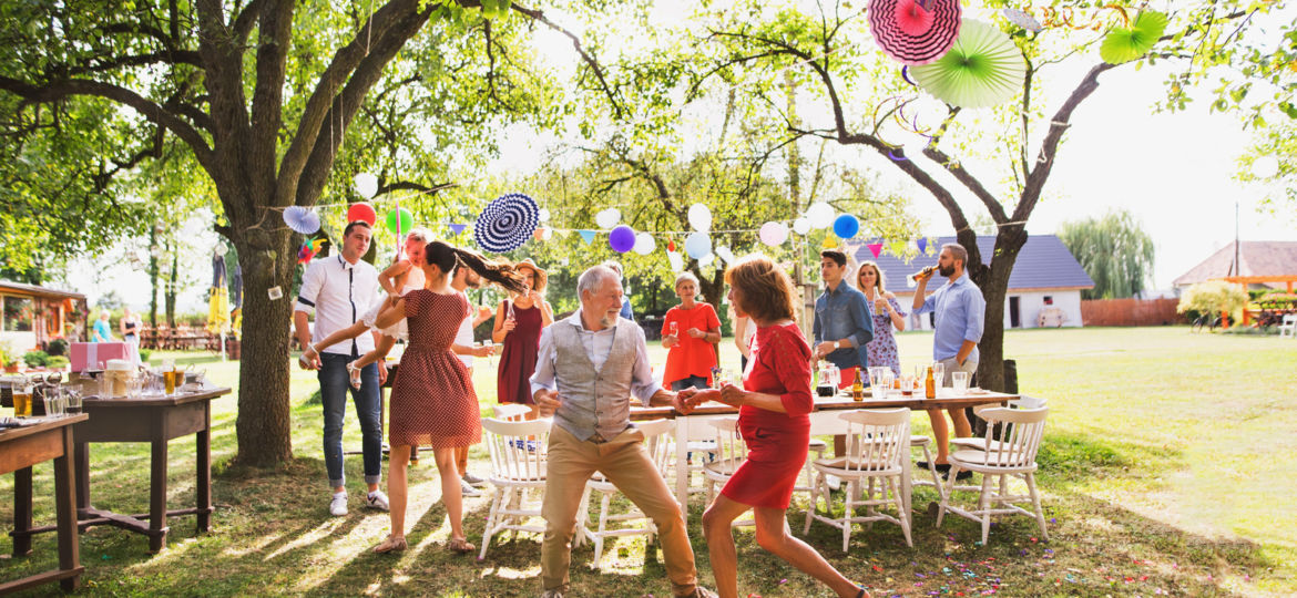 A senior couple and family dancing on a garden party outside in the backyard.
